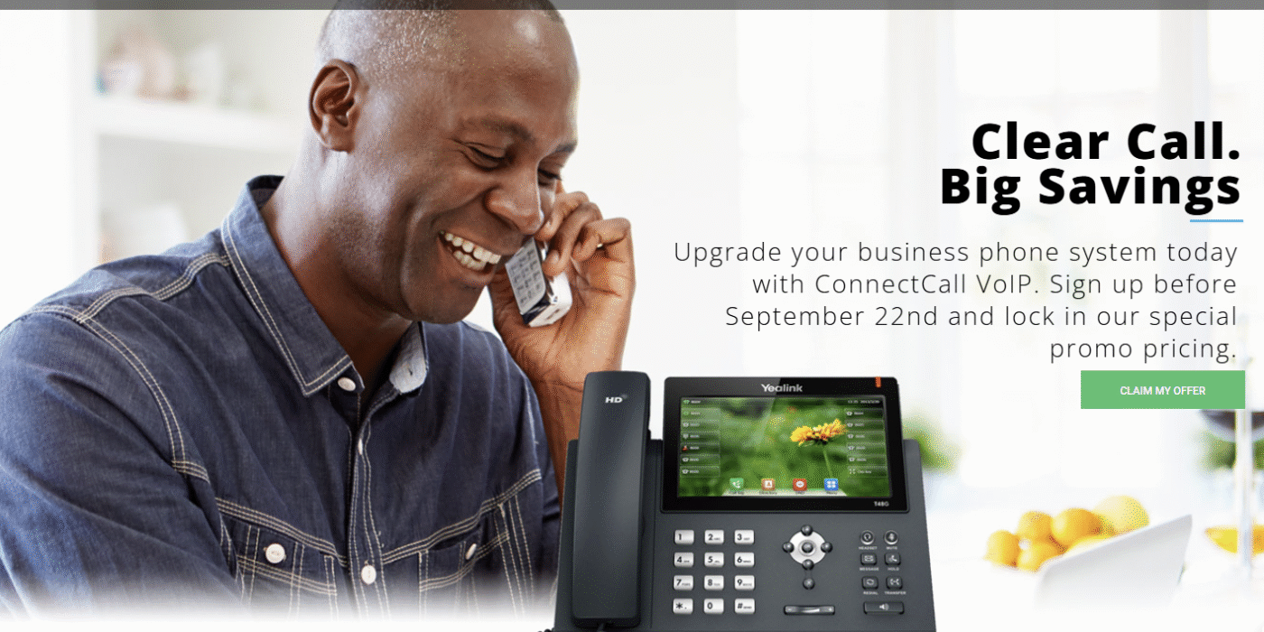 Man smiling while using a VoIP phone, showcasing ConnectCall's business phone system with promotional text about upgrading and savings.